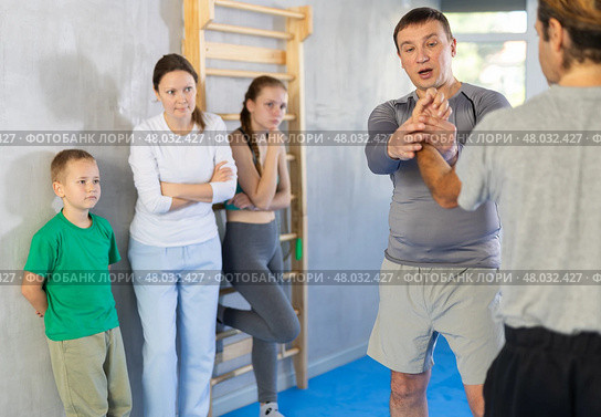 Man coach shows family students technique of performing painful modus with help of wringing hand. Стоковое фото, фотограф Яков Филимонов / Фотобанк Лори
