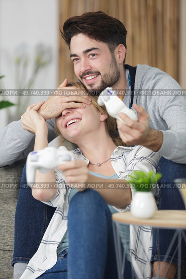 man covering girlfriends eyes during game of playstation. Стоковое фото, агентство Ingram Publishing / Фотобанк Лори