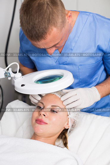 Man doctor is analysing skin on face of female patient before the procedure. Стоковое фото, фотограф Яков Филимонов / Фотобанк Лори