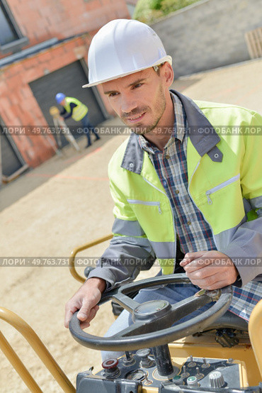 man driving driller vibrator on asphalting road. Стоковое фото, агентство Ingram Publishing / Фотобанк Лори