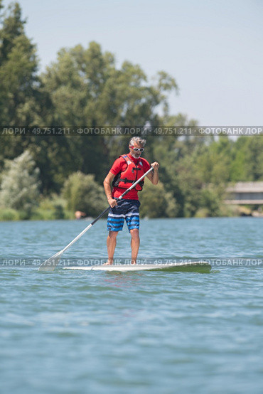 man enjoying a ride on the lake with paddleboard. Стоковое фото, агентство Ingram Publishing / Фотобанк Лори