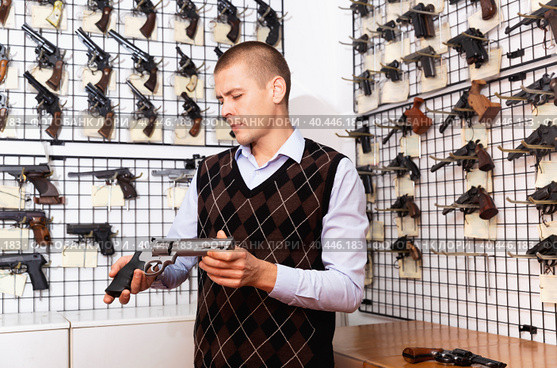 Man examining sporting revolvers before buying in gun store. Стоковое фото, фотограф Яков Филимонов / Фотобанк Лори