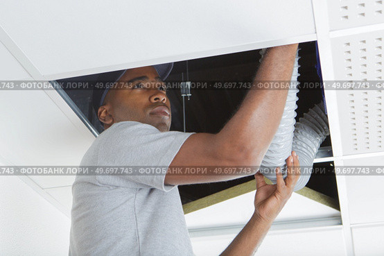 Man fiiting plastic hose into roof space. Стоковое фото, агентство Ingram Publishing / Фотобанк Лори