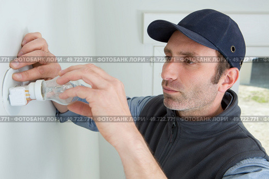 man fitting a low energy cfl light bulb. Стоковое фото, агентство Ingram Publishing / Фотобанк Лори