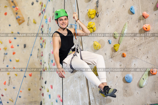man in safety helmet and with safety rope hangs near climbing wall in gym. Стоковое фото, фотограф Яков Филимонов / Фотобанк Лори