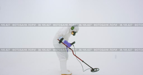 Man in white chemical protection suit holds metal detector. Стоковое видео, видеограф Aleksey Kidisyuk / Фотобанк Лори