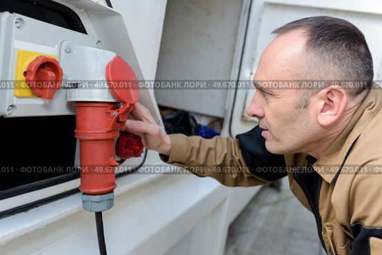 man inserts a plug from the car battery charger. Стоковое фото, агентство Ingram Publishing / Фотобанк Лори