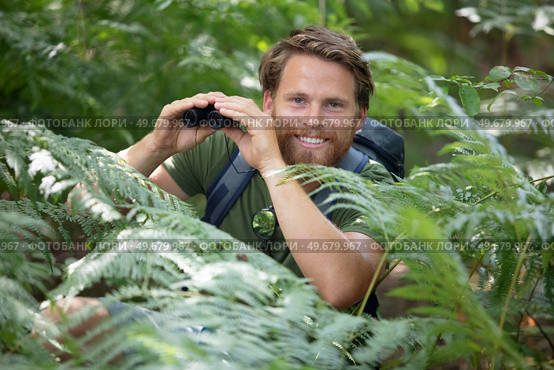 man looks through binoculars in nature. Стоковое фото, агентство Ingram Publishing / Фотобанк Лори