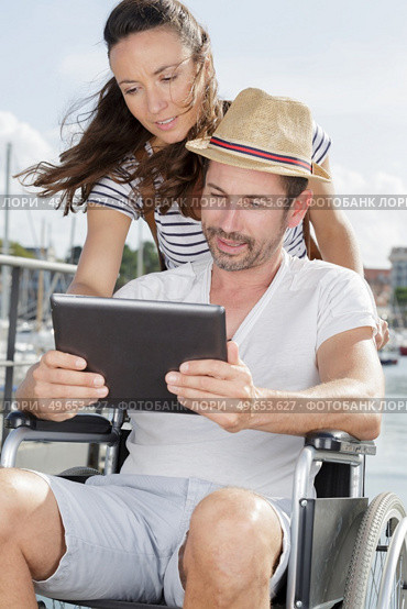 man on wheelchair with tablet in hands outdoors. Стоковое фото, агентство Ingram Publishing / Фотобанк Лори