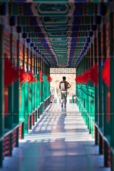 Man passing through the beautiful corridor with Chinese traditional ancient pavilions. Imperial City in the center of Beijing, China (2024 год). Стоковое фото, фотограф Кекяляйнен Андрей / Фотобанк Лори
