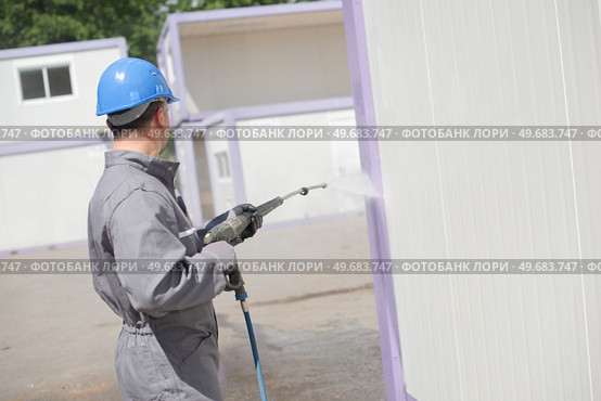 Man power washing portable cabin. Стоковое фото, агентство Ingram Publishing / Фотобанк Лори
