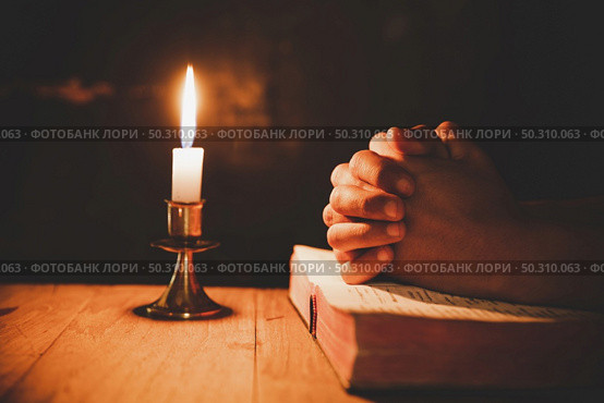 man praying on the Bible in the light candles selective focus. Стоковое фото, агентство Ingram Publishing / Фотобанк Лори