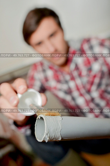 Man putting plastic glue on end of pvc pipe. Стоковое фото, агентство Ingram Publishing / Фотобанк Лори