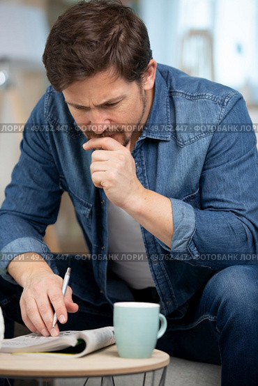 man reading magazine book on sofa reader holding a pen. Стоковое фото, агентство Ingram Publishing / Фотобанк Лори