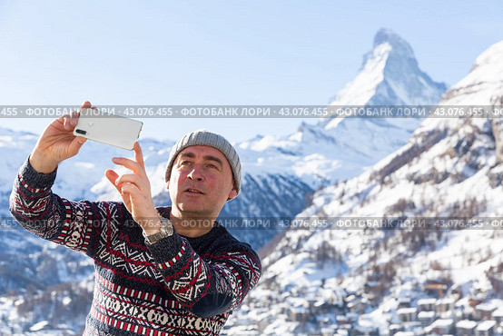 Man recording video with phone while traveling in winter Swiss Alps. Стоковое фото, фотограф Яков Филимонов / Фотобанк Лори