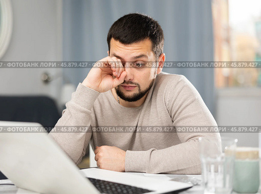 Man rubs tired eyes with his hands after a long work at laptop at home. Стоковое фото, фотограф Яков Филимонов / Фотобанк Лори