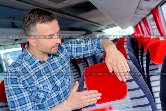 Man securing protector to bus headrest. Стоковое фото, агентство Ingram Publishing / Фотобанк Лори
