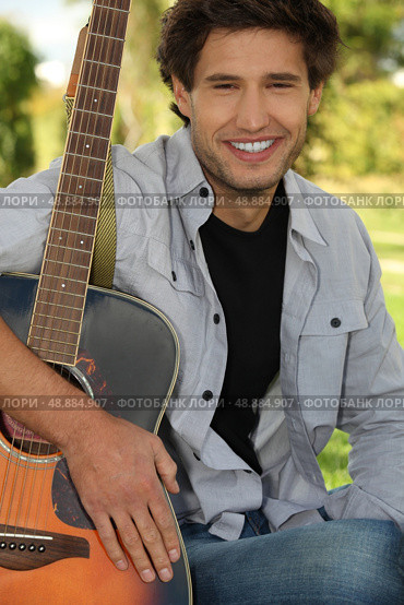 Man sitting in park with guitar. Стоковое фото, агентство Ingram Publishing / Фотобанк Лори