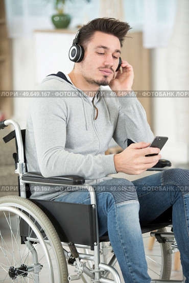 man sitting in wheelchair listening music through headphones. Стоковое фото, агентство Ingram Publishing / Фотобанк Лори