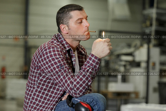 man smokes a cigar across from the factory. Стоковое фото, агентство Ingram Publishing / Фотобанк Лори