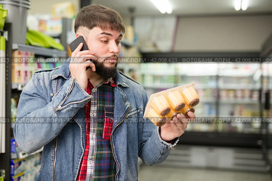 man talking on smartphone about purchasing of yogurts. Стоковое фото, фотограф Яков Филимонов / Фотобанк Лори