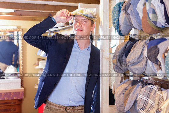 man try on trilby hat and looking at mirror in headwear shop. Стоковое фото, фотограф Яков Филимонов / Фотобанк Лори