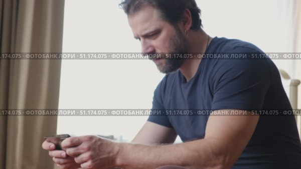 Man using his cellphone. Handsome guy use mobile phone at home. Male browses social networks, gaming, does shopping online, chats with friends, writes or reads messages. Close up. 4k video footage. Стоковое видео, видеограф Марина Демидюк / Фотобанк Лори