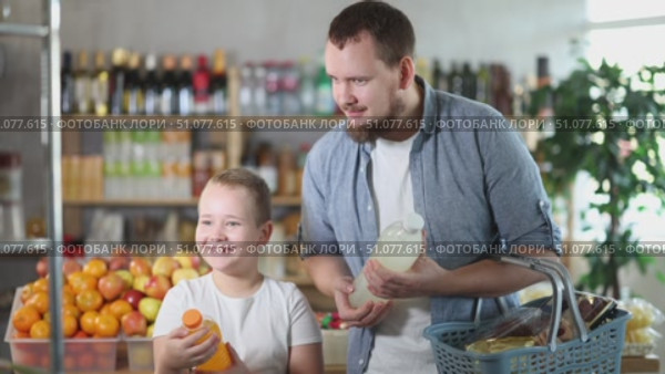 Man with son hold packages plastic bottle and choose consider carbonated beverage in store. Стоковое видео, видеограф Яков Филимонов / Фотобанк Лори