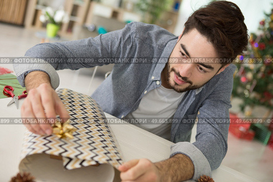 man wrapping christmas presents. Стоковое фото, агентство Ingram Publishing / Фотобанк Лори