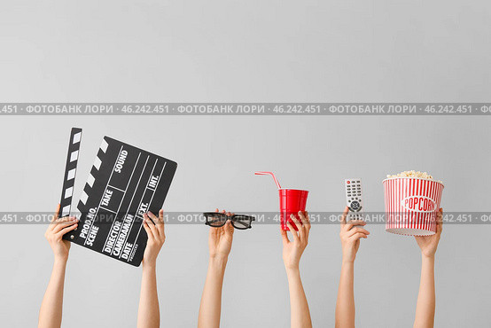 Many hands with popcorn, drink, remote control, movie clapper and eyeglasses on grey background. Стоковое фото, фотограф Pixel_shot / Фотобанк Лори