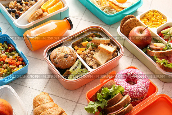 Many lunchboxes with different delicious food and bottle of juice on white tile background. Стоковое фото, фотограф Pixel_shot / Фотобанк Лори