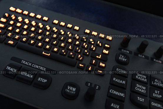Marine navigation simulator. Close-up of an advanced control panel with glowing keyboard and function buttons, illuminated by orange lights. Стоковое фото, фотограф EugeneSergeev / Фотобанк Лори