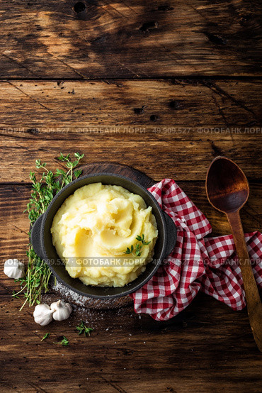 Mashed potatoes, boiled puree in cast iron pot on dark wooden rustic background, top view. Стоковое фото, агентство Ingram Publishing / Фотобанк Лори