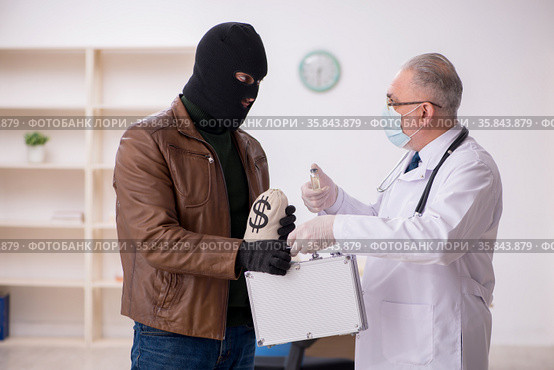 Masked man burglar bribing old doctor for getting vaccine. Стоковое фото, фотограф Elnur / Фотобанк Лори