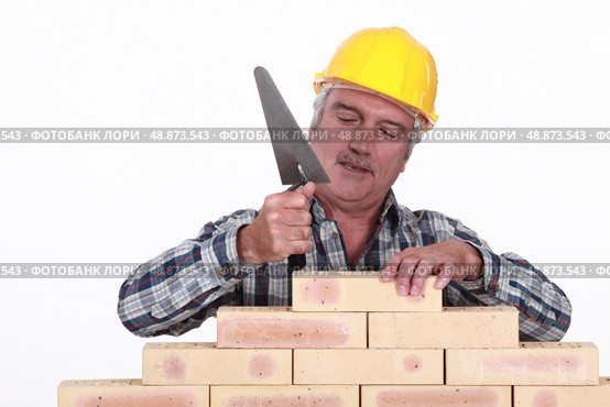 Mason tapping brick into place. Стоковое фото, агентство Ingram Publishing / Фотобанк Лори