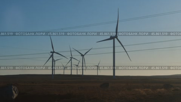 Massive propeller blades of a wind turbine spin, generating clean energy from the wind in the heart of the wilderness. Стоковое видео, видеограф Strunov David / Фотобанк Лори