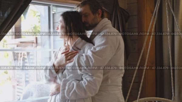 Mature couple in a white bathrobes hugging each other kissing at home room. Intimate Moment. Tender embrace shared between a loving middle age man and woman, husband and wife. Deep love. Vacation. Стоковое видео, видеограф Марина Демидюк / Фотобанк Лори