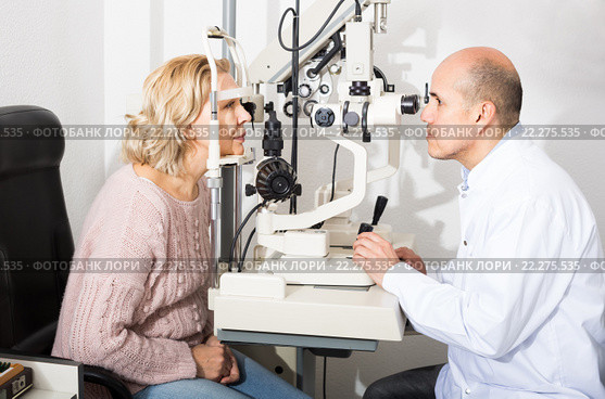 Mature optician examinating eyesight with aid of slit lamp. Стоковое фото, фотограф Яков Филимонов / Фотобанк Лори