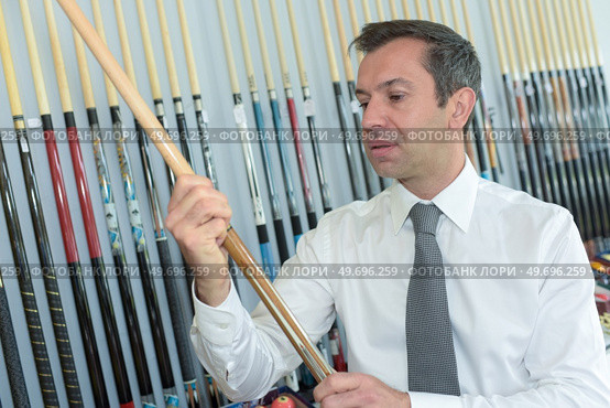 mature seller holding pool cue in his store. Стоковое фото, агентство Ingram Publishing / Фотобанк Лори