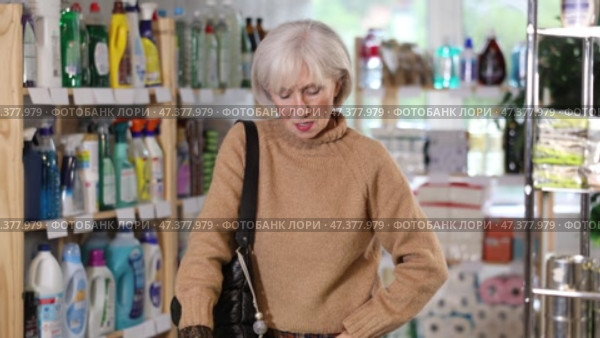 Mature woman chooses an ironing board in a store with household chemicals. Стоковое видео, видеограф Яков Филимонов / Фотобанк Лори