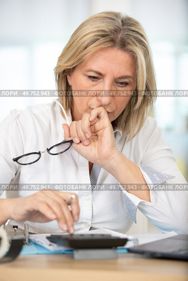 mature woman with calculator makes up her personal budget. Стоковое фото, агентство Ingram Publishing / Фотобанк Лори