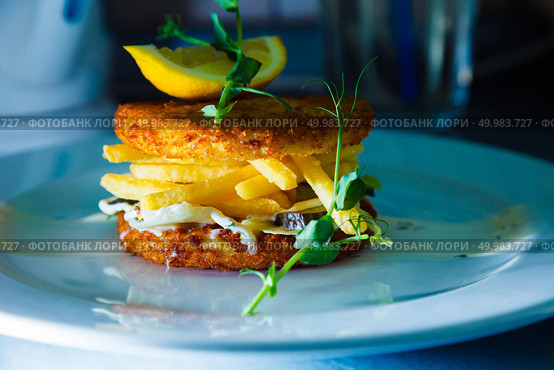 meat hamburger with french fries and pickled cucumbers decorated piece of lemon. Стоковое фото, агентство Ingram Publishing / Фотобанк Лори