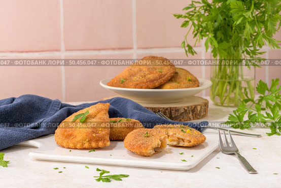Meat patties and parsley leaves on white ceramic dishes in a kitchen counter top. Стоковое фото, агентство Ingram Publishing / Фотобанк Лори