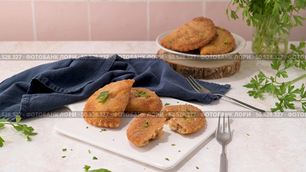 Meat patties and parsley leaves on white ceramic dishes in a kitchen counter top. Стоковое фото, агентство Ingram Publishing / Фотобанк Лори