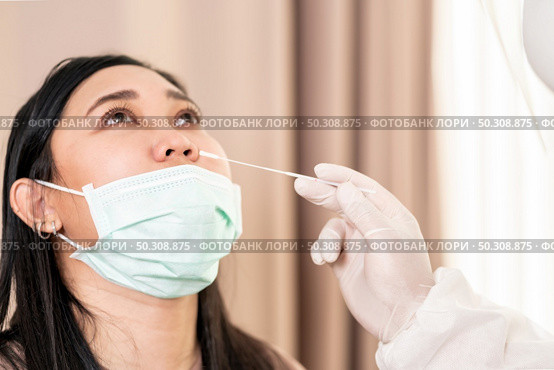 Medical staff with PPE suit test coronavirus covid-19 to asian woman by nose swab at hospital. COVID-19 testing health care concept. Стоковое фото, агентство Ingram Publishing / Фотобанк Лори