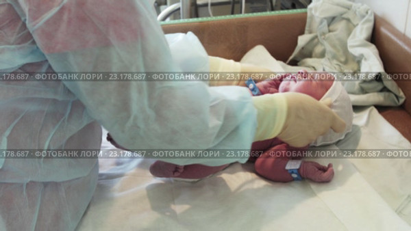 Медсестра надевает одноразовую шапочку на новорождённого на пеленальном столике в роддоме. Стоковое видео, видеограф Александр Багно / Фотобанк Лори