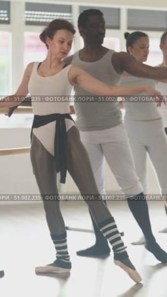 Men and women stand in second position near ballet barre during group training in a dance studio. Стоковое видео, видеограф Яков Филимонов / Фотобанк Лори