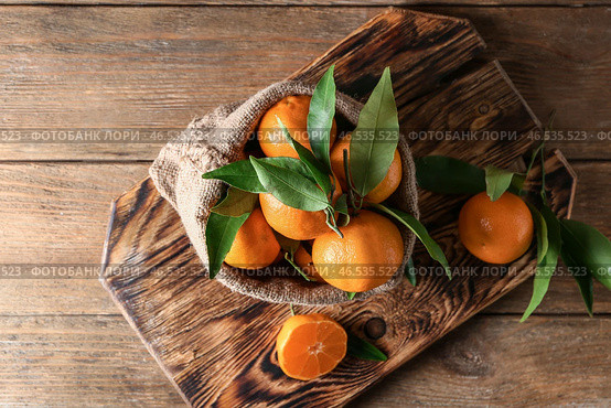 Мешочек с вкусными сочными мандаринами на деревянной доске. Стоковое фото, фотограф Pixel_shot / Фотобанк Лори