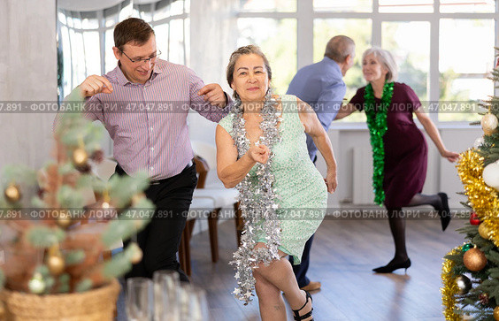 Middle-aged man and elderly woman are dancing contemporary twist in couple in Christmas atmosphere. Стоковое фото, фотограф Яков Филимонов / Фотобанк Лори