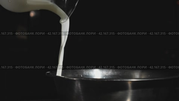 Milk from a glass jug pours in slow motion video into a stainless steel plate. Стоковое видео, видеограф Даниил Хабаров / Фотобанк Лори